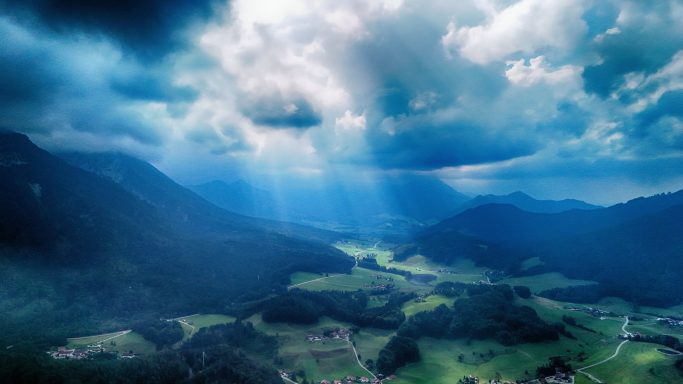 Landschap met mistige bergen, een vallei en stralen zonlicht door de wolken.
