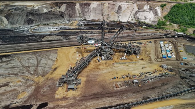 Luchtfoto van een mijnwerkzaamheden met zware machines en een verfijnde structuur.