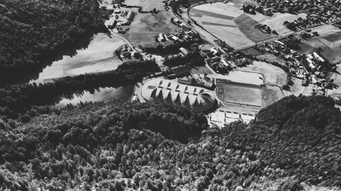 Luchtfoto van een landschap met een rivieroever, velden en een dorp.