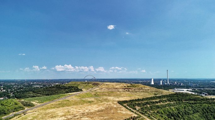 Uitzicht op een heuvel met een heldere lucht en industrie op de achtergrond.