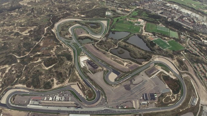 Luchtfoto van een racecircuit met bochten en groene omliggende gebieden.