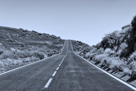 Een rechte, desolate weg die omhoog leidt met bergen aan beide zijden.