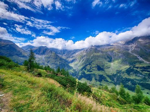 Uitzicht op een berglandschap met groene valleien en een heldere blauwe lucht.