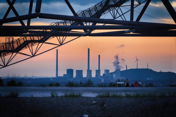 Silhouetten van fabrieks chimneys tegen een kleurrijke zonsondergang.