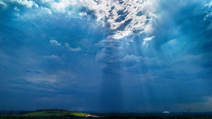 Een dramatisch wolkenlandschap met zonnestralen die door de lucht breken.