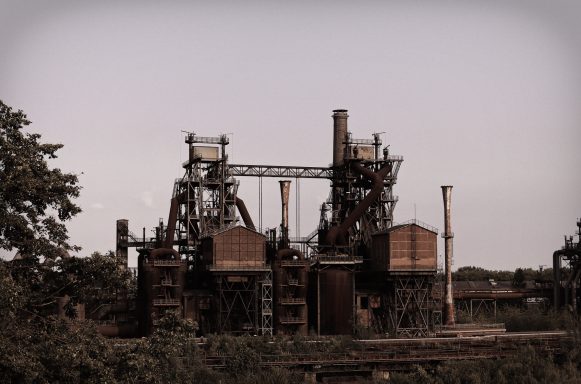 Oude industriële fabriek met hoge schoorstenen en verroeste structuren.